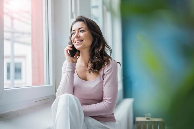 Woman talking on the phone by the window