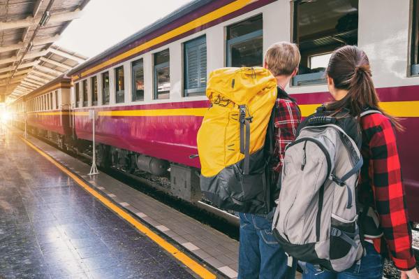 Dos personas esperando a montar en el tren en una estación.